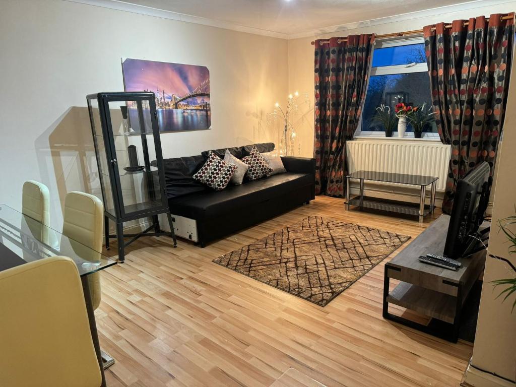 a living room with a black couch and a table at EL MET GLOBAL APARTMENT in Slades Green