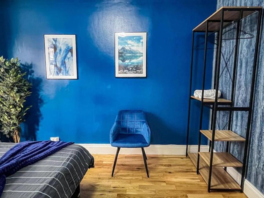 ein Schlafzimmer mit einer blauen Wand und einem blauen Stuhl in der Unterkunft East London Townhouse by Harlington in London