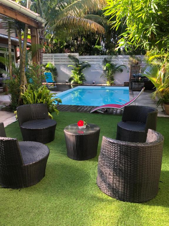 a group of wicker chairs and tables in front of a pool at Villa Tikoinjoli in Saint-Pierre