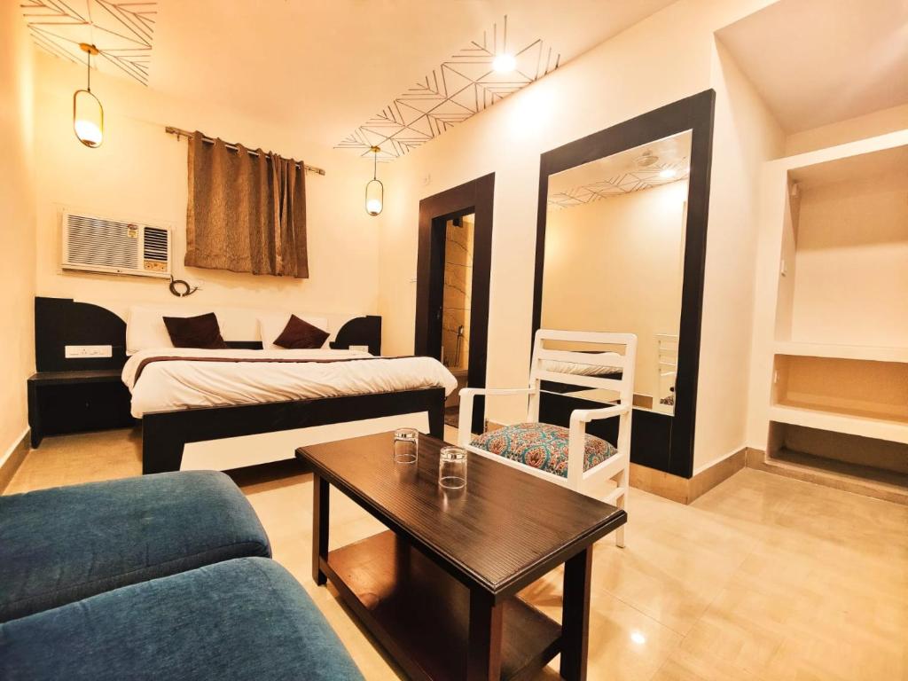 ein Wohnzimmer mit einem Sofa, einem Bett und einem Tisch in der Unterkunft Hotel Mahamaya in Satna