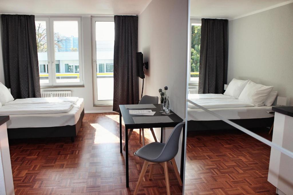 una camera d'albergo con due letti e un tavolo con sedie di Hometown-Apartments a Heidelberg