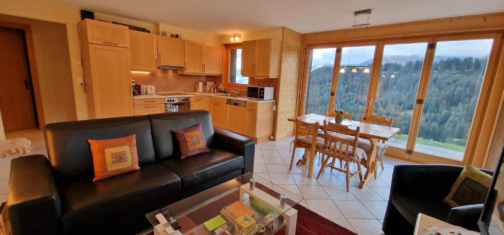 a living room with a couch and a table and a kitchen at Majis 4 in Champoussin