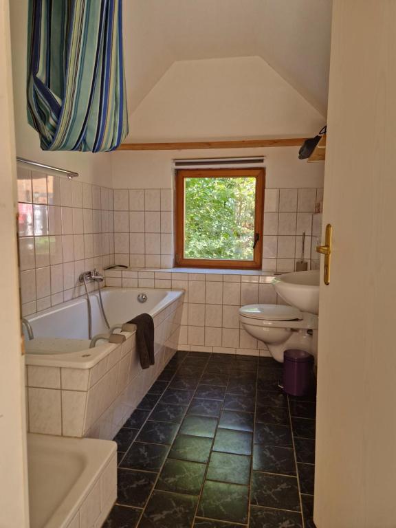 a bathroom with a tub and a toilet and a sink at Gästehaus Lichtblick in Herrenhof