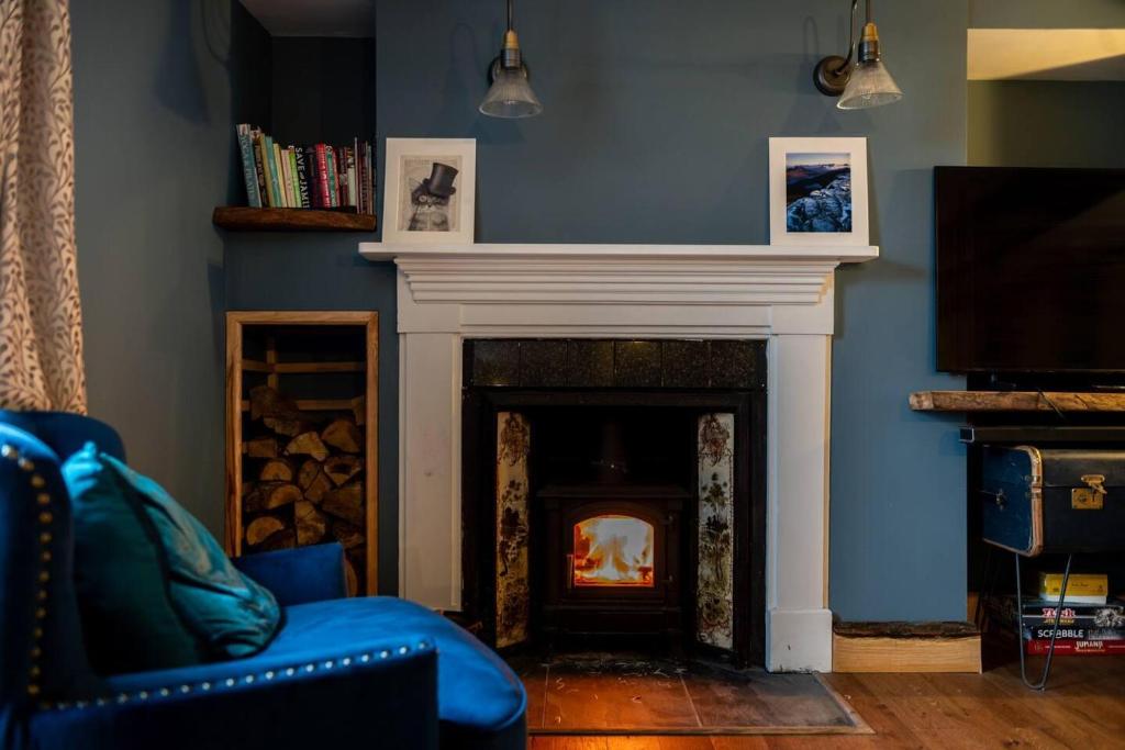 ein Wohnzimmer mit einem Kamin und einer blauen Wand in der Unterkunft 3 bedroom Quirky Luxurious Cottage With Hot Tub in Heathfield