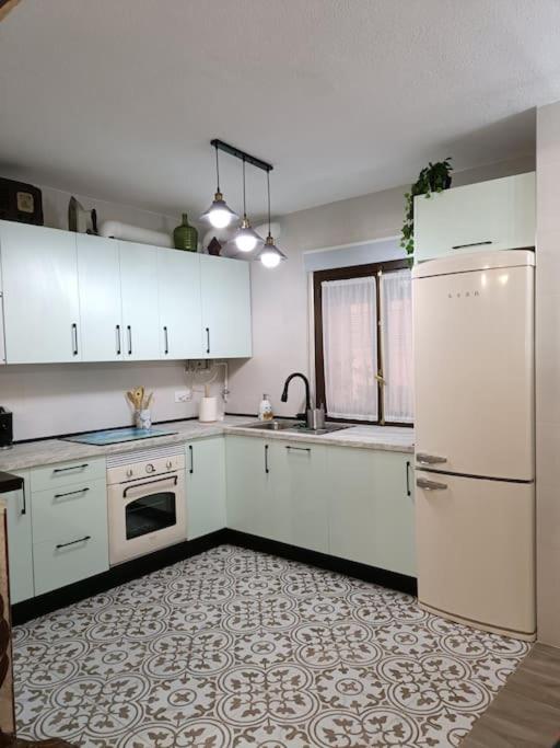 uma cozinha com armários brancos e um frigorífico branco em La casona de la Azucena em Guadalajara