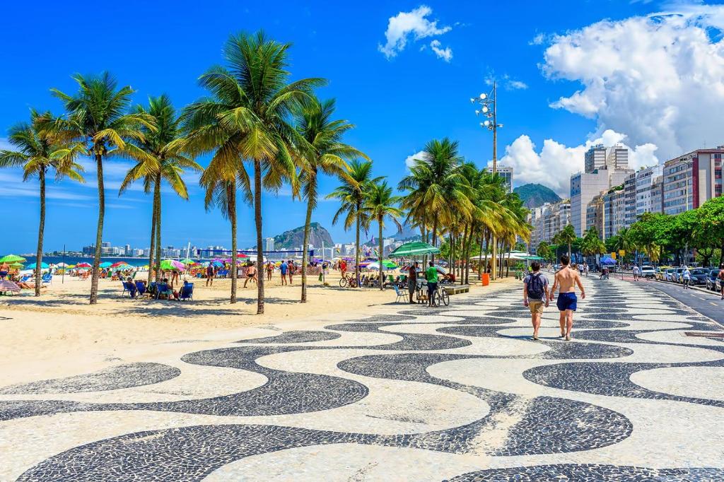 a beach with palm trees and people walking on a sidewalk at Residencial -Copacabana -Praia in Rio de Janeiro