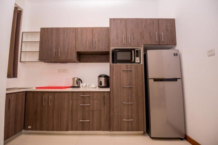 uma cozinha com armários de madeira e um frigorífico em Kings Hantana em Kandy