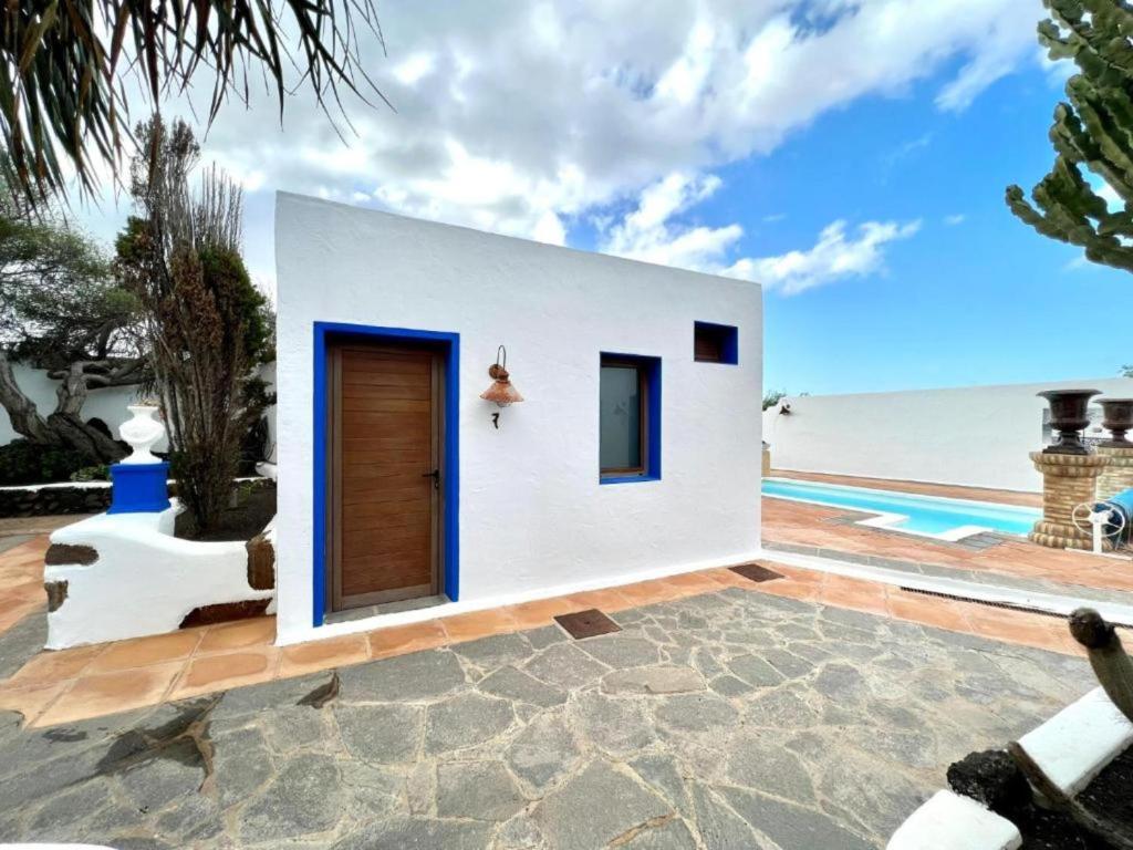 una casa blanca con una puerta azul junto al océano en Doble con desayuno incluido, Wifi gratis, estupenda piscina en Yaiza en Yaiza