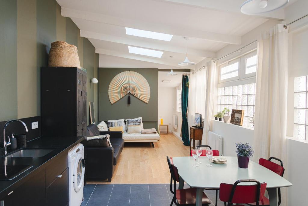 eine Küche und ein Wohnzimmer mit einem Tisch und Stühlen in der Unterkunft L'atelier de Luc, Paris 20eme in Paris