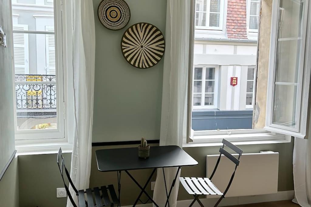 une table et des chaises dans une pièce avec des fenêtres dans l'établissement Coup de cœur à Trouville, à Trouville-sur-Mer