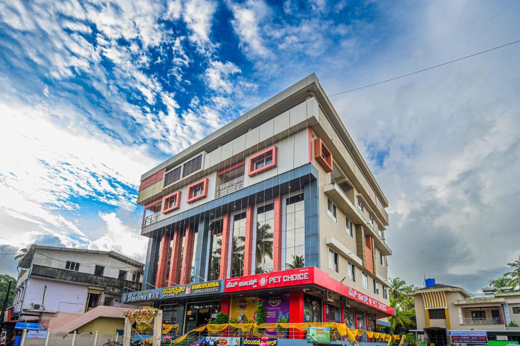 a building on a city street with a cloudy sky at Hotel Samudyatha Inn And Suites in Kundapur