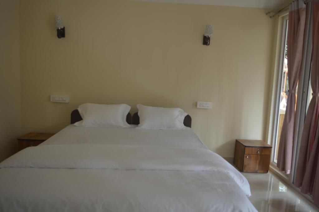 a bedroom with a white bed with two pillows and a window at Taste of Nature in Canacona