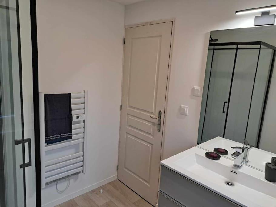 a white bathroom with a sink and a mirror at Gîte des deux L 