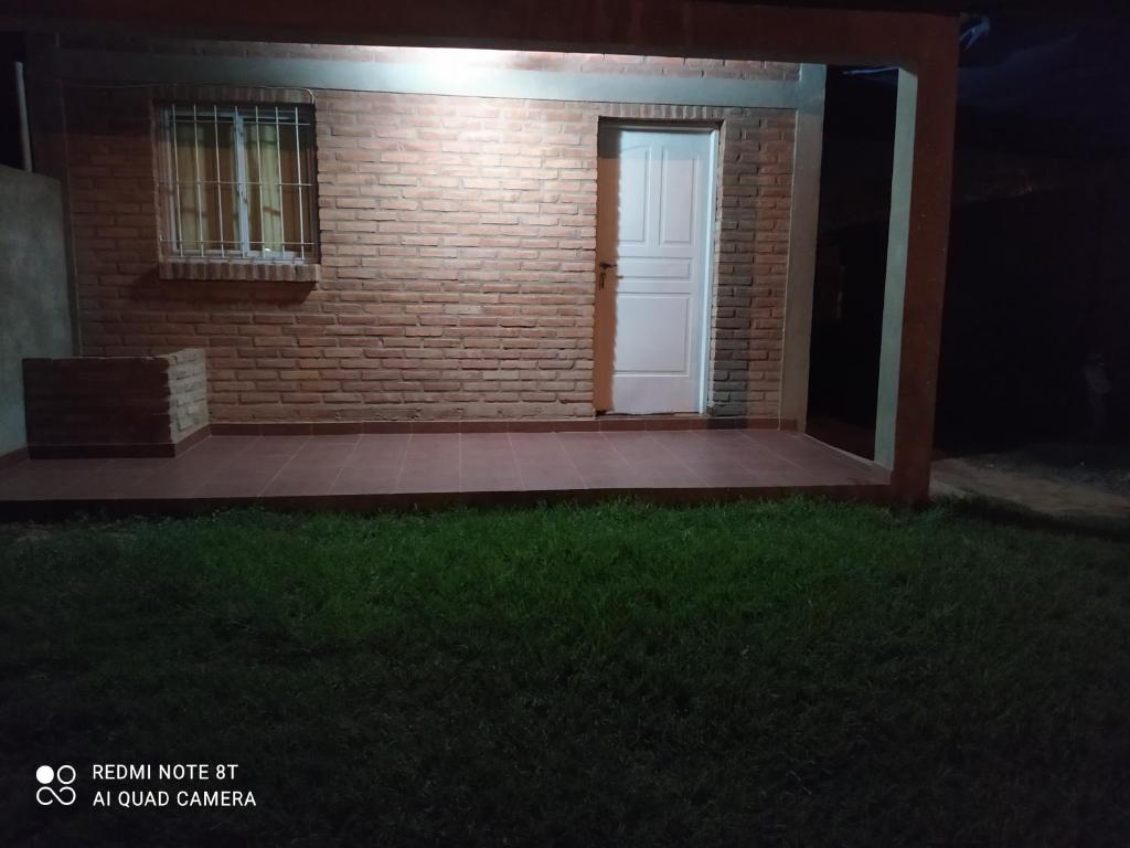 a brick house with a white door and a grass field at Luna in Villa Cura Brochero