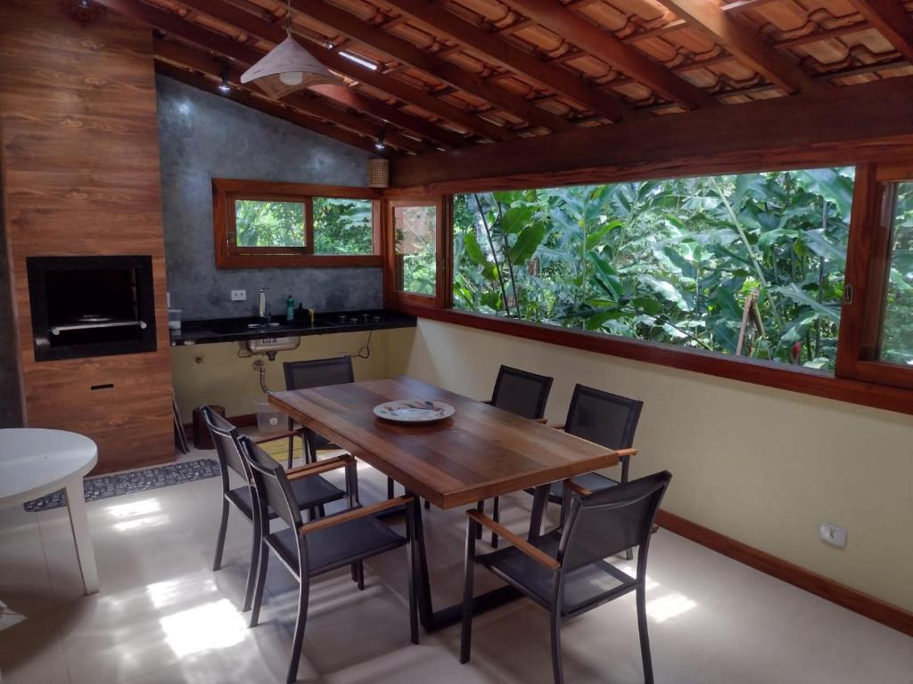 a dining room with a wooden table and chairs at CASA PRUMIRIM in Ubatuba