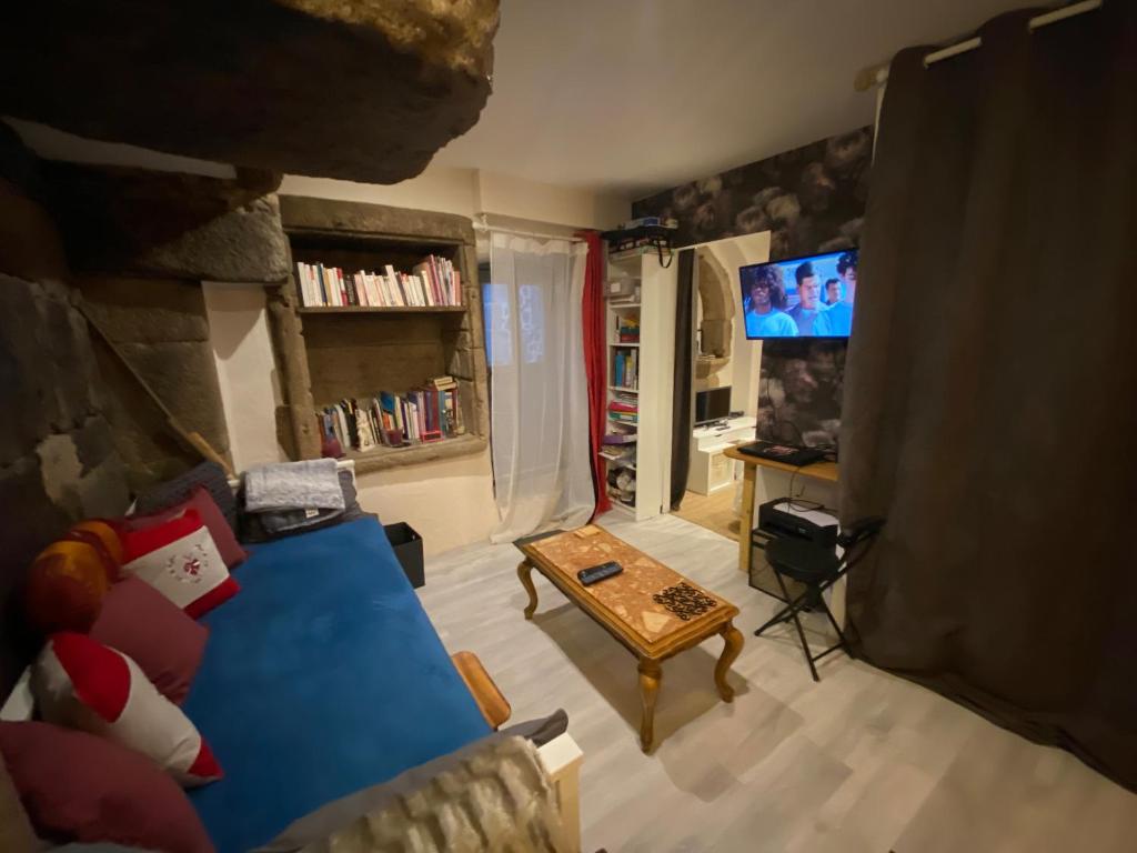 a living room with a blue couch and a tv at Avélia Bonnevie in Murat