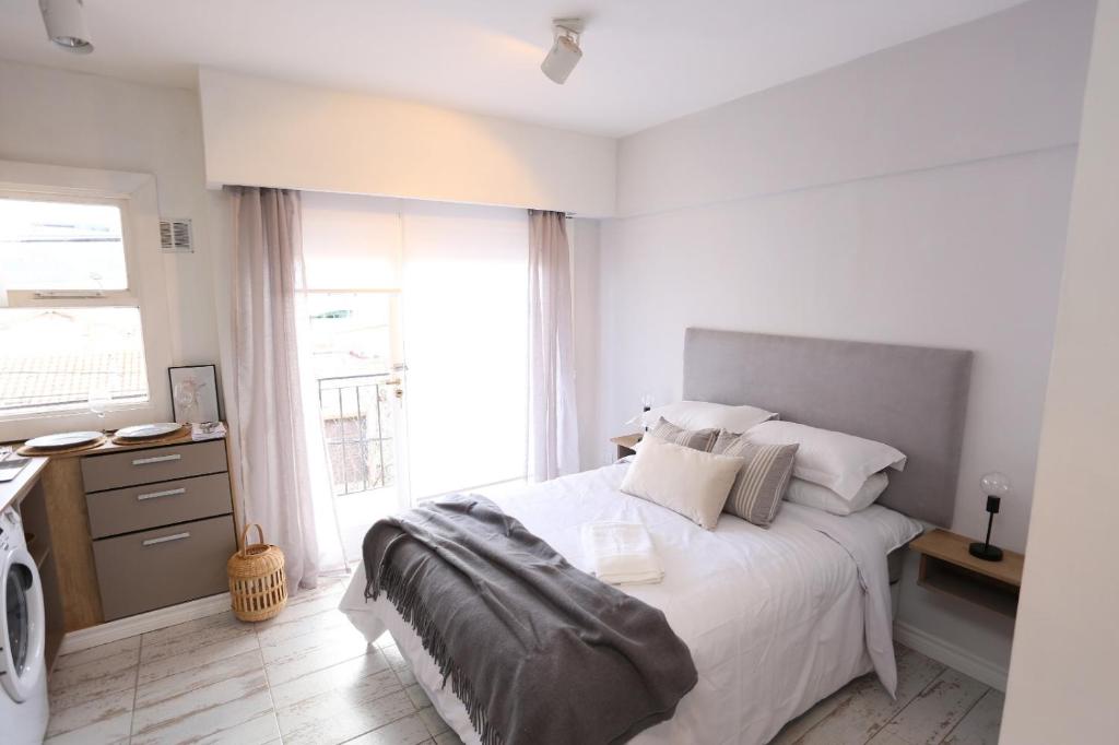 Habitación blanca con cama y ventana en Departamento de 1 ambiente en Mar del Plata