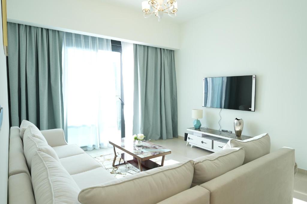 uma sala de estar com um sofá branco e uma televisão em Brown Stone Holiday Homes Act em Dubai