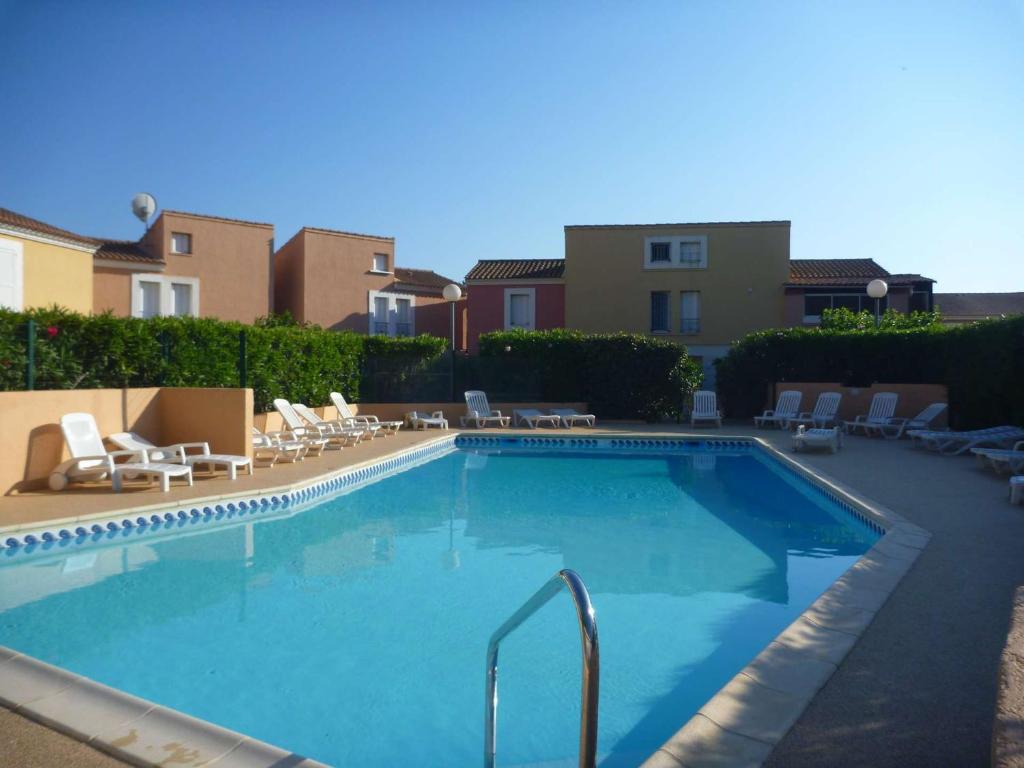une piscine avec des chaises longues et un complexe hôtelier dans l'établissement Appartement 6 pers. avec piscine, tennis et pétanque - Marseillan - FR-1-387-36, à Marseillan