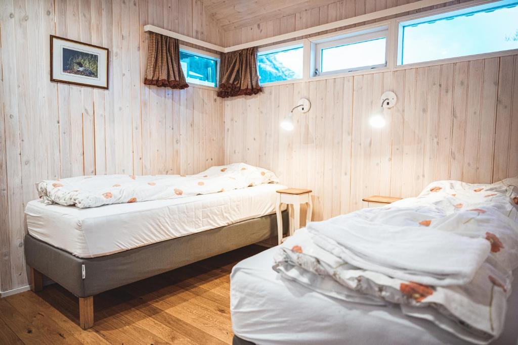 two beds in a room with wooden walls and windows at Old Cottages in Höfn