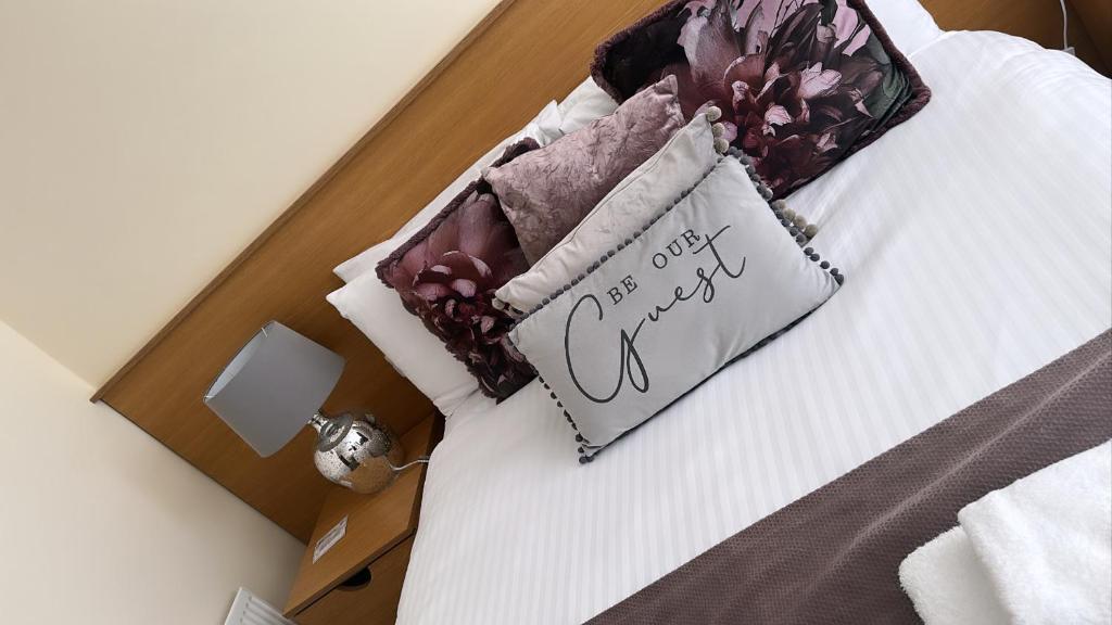 a bed with a pillow with a sign on it at The Hedges Hotel in Stranocum