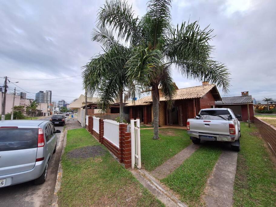 un camión blanco estacionado al lado de una casa con una palmera en Casa com quintal próxima de Torres, en Passo de Torres