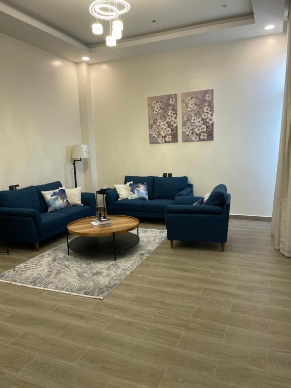 una sala de estar con 2 sofás azules y una mesa. en شقة عائلية خاصة, en Dhahran