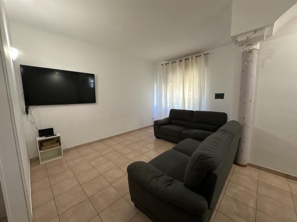 Olbia via modena في أولبيا: غرفة معيشة مع أريكة وتلفزيون بشاشة مسطحة