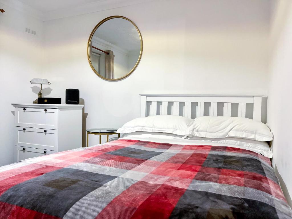 a bedroom with a bed with a plaid blanket and a mirror at Immaculate 2-Bed Apartment in Rochester in Rochester