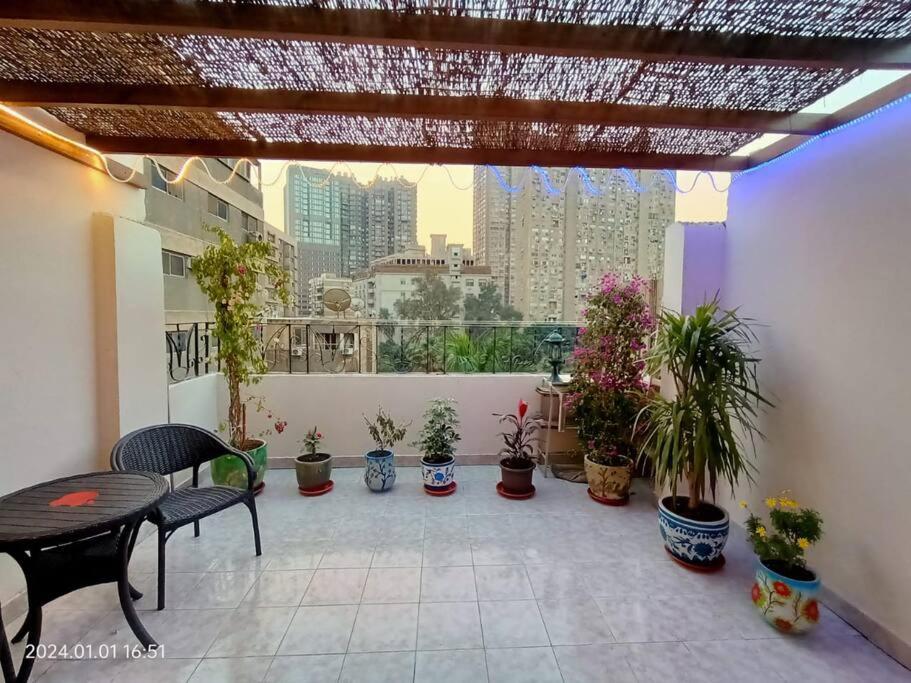 un patio con mesa, sillas y macetas en Lovely & Calm Rooftop in Maadi 5 min from the Nile, en El Cairo