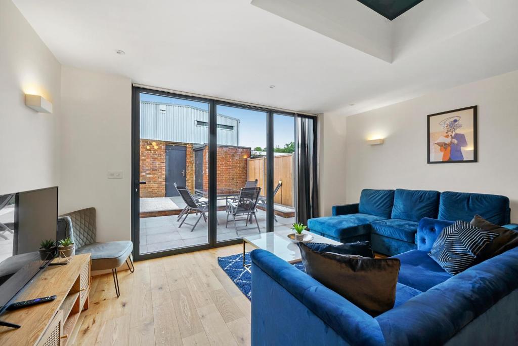 Luxurious 5 Bed House in London - Pool Table في West Dulwich: غرفة معيشة مع أريكة زرقاء وتلفزيون