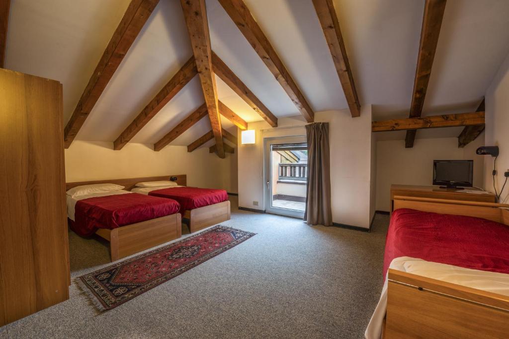 sypialnia z dwoma łóżkami i telewizorem w obiekcie Hotel Drago w mieście Mezzocorona