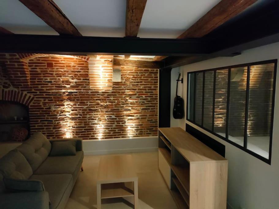 un salon avec un canapé et un mur de briques dans l'établissement Appartement Capitole hypercentre, à Toulouse