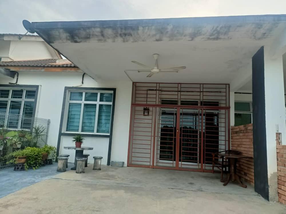 a house with a red door and a ceiling fan at Azaliza Homestay in Ayer Keroh