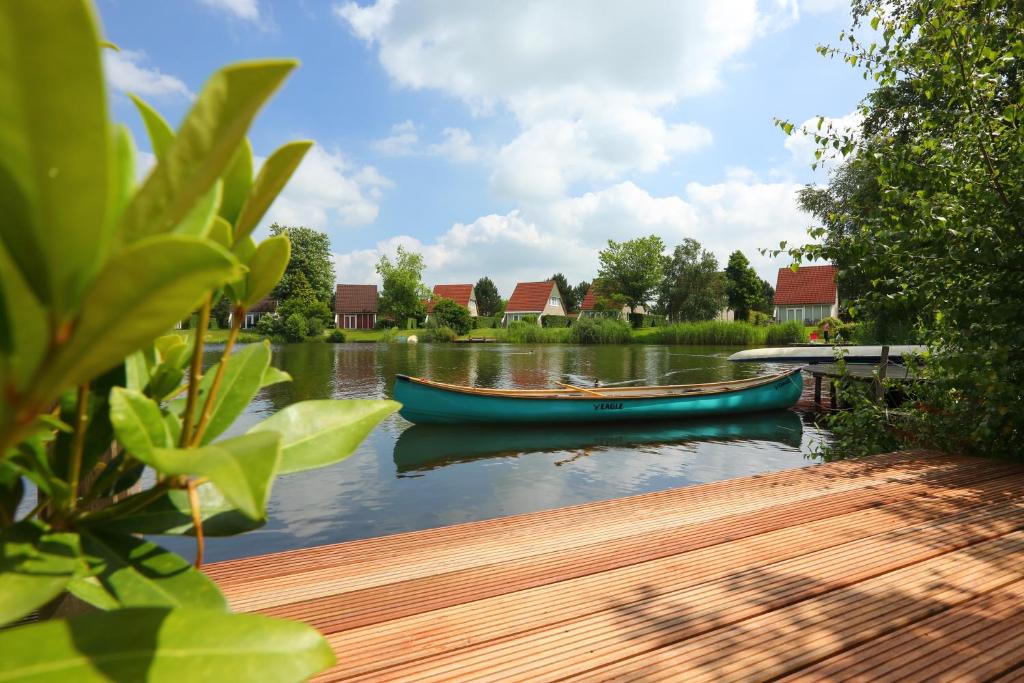um barco sentado na água ao lado de uma doca em Summio Vakantiepark Emslandermeer em Vlagtwedde