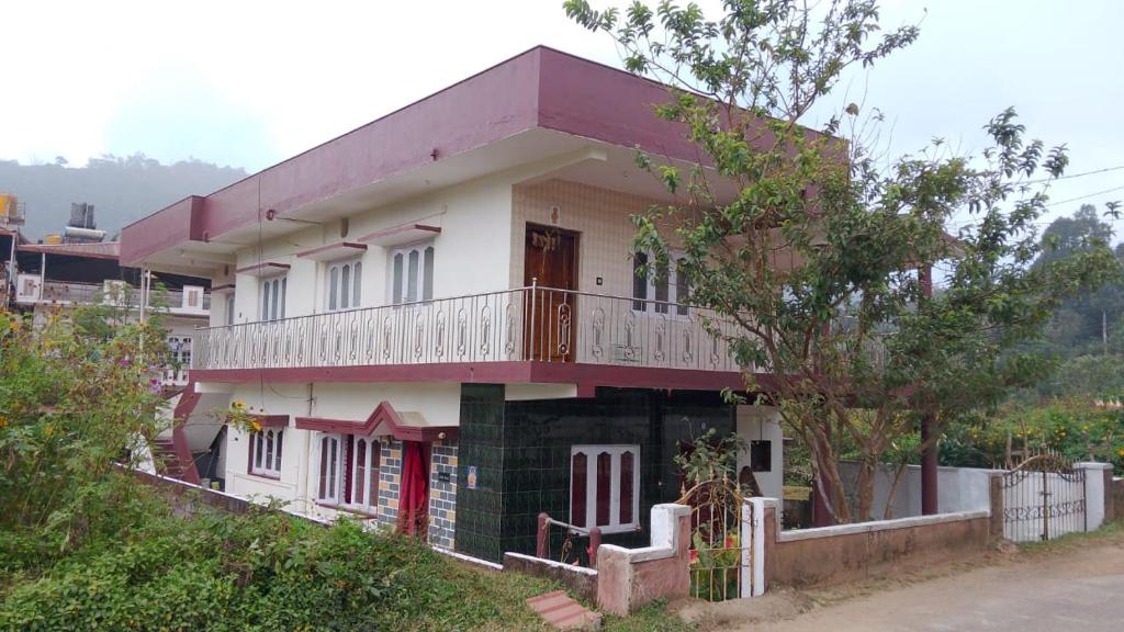 K K homestay في ماديكيري: منزل فوقه شرفة