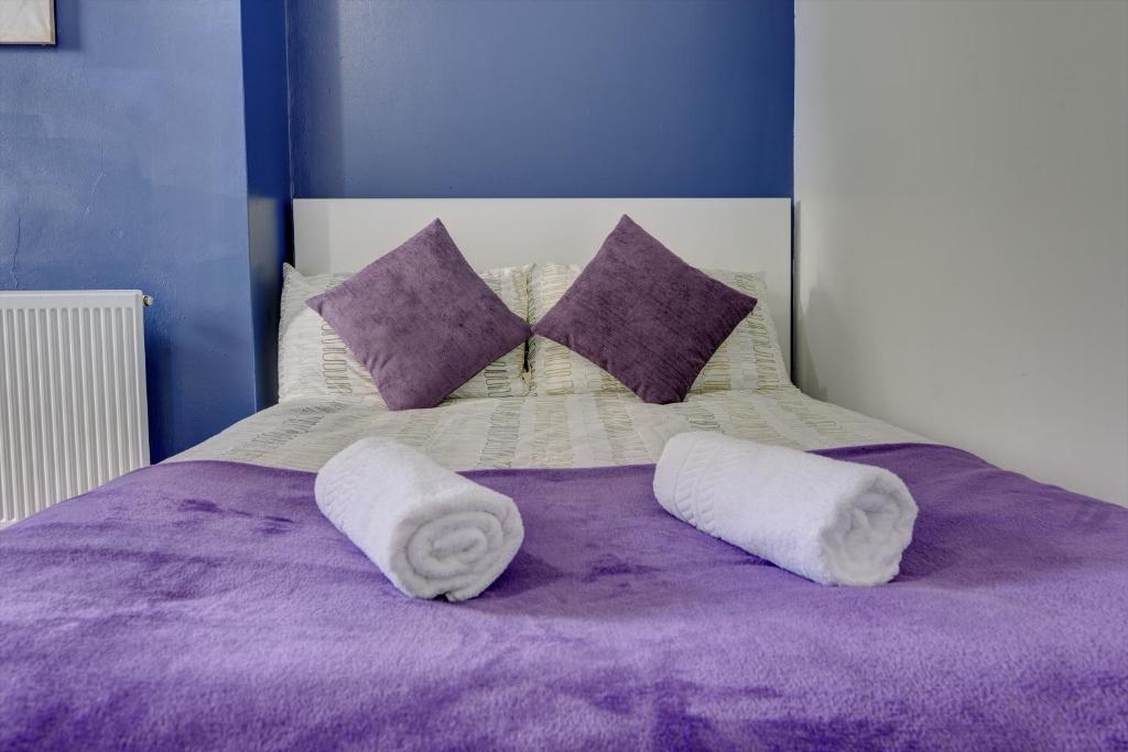 Cosy 3BR Gem, Sleeps 6, Near Town Centre في كوفينتري: سرير أرجواني عليه منشفتين بيضاء