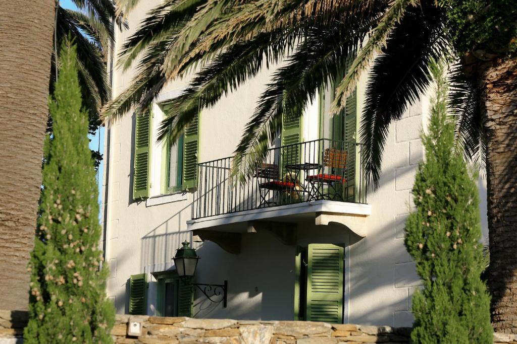 a white building with a balcony and palm trees at Demeure Castel Brando Hôtel & Spa in Erbalunga