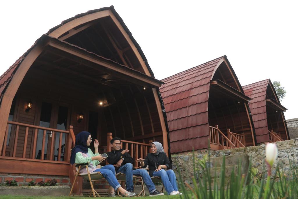 three people sitting in chairs in front of a house at The Hills Kerinci in Kayu Aro