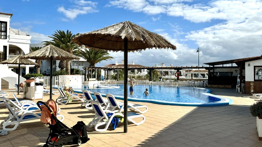un complejo con piscina con sillas y sombrilla en Serena Vista Golf 791 - Appartamento Confortevole a Amarilla Golf, en San Miguel de Abona