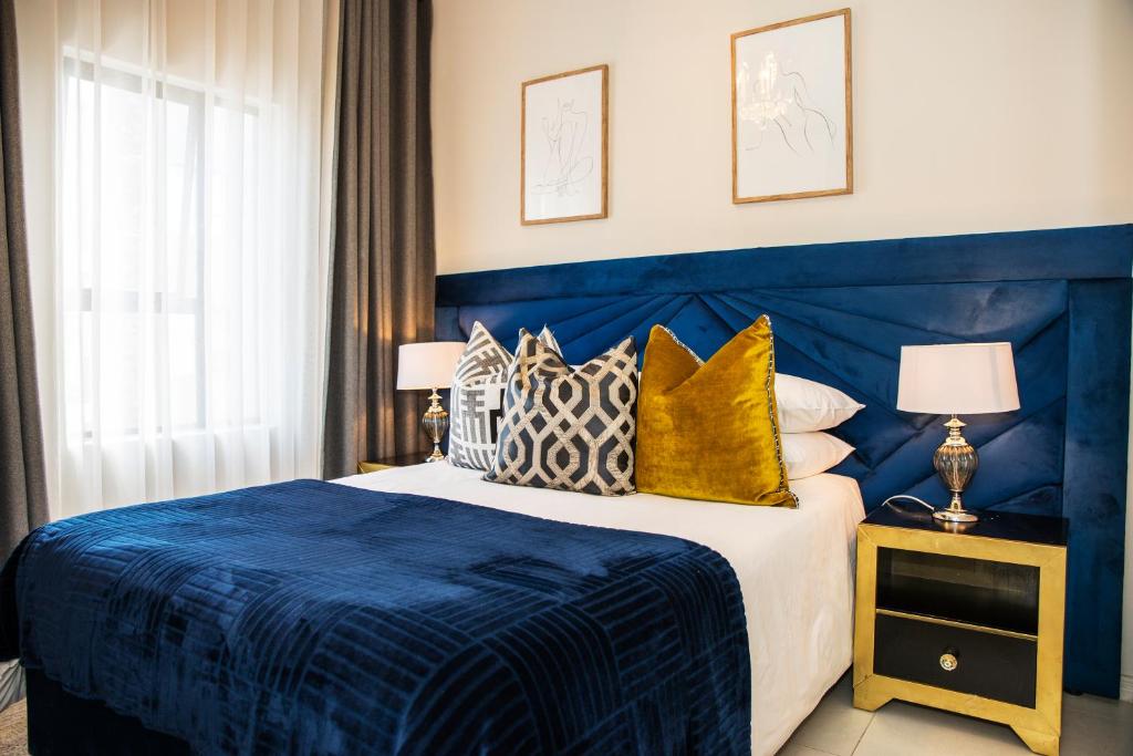 a blue bedroom with a bed with a blue headboard at Eirini Elegant - Artemis Apartment Carlswald in Midrand