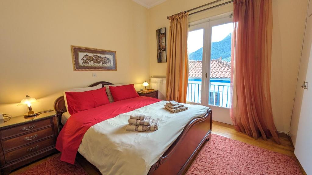 Un dormitorio con una cama con almohadas rojas y una ventana en Sapho's House, en Leonidio