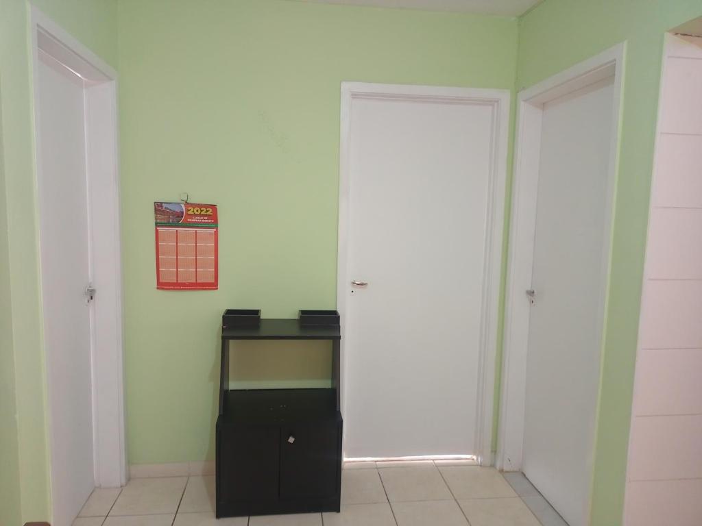 Zimmer mit zwei weißen Türen und einem Tisch in der Unterkunft Comodidade sempre in São José dos Campos