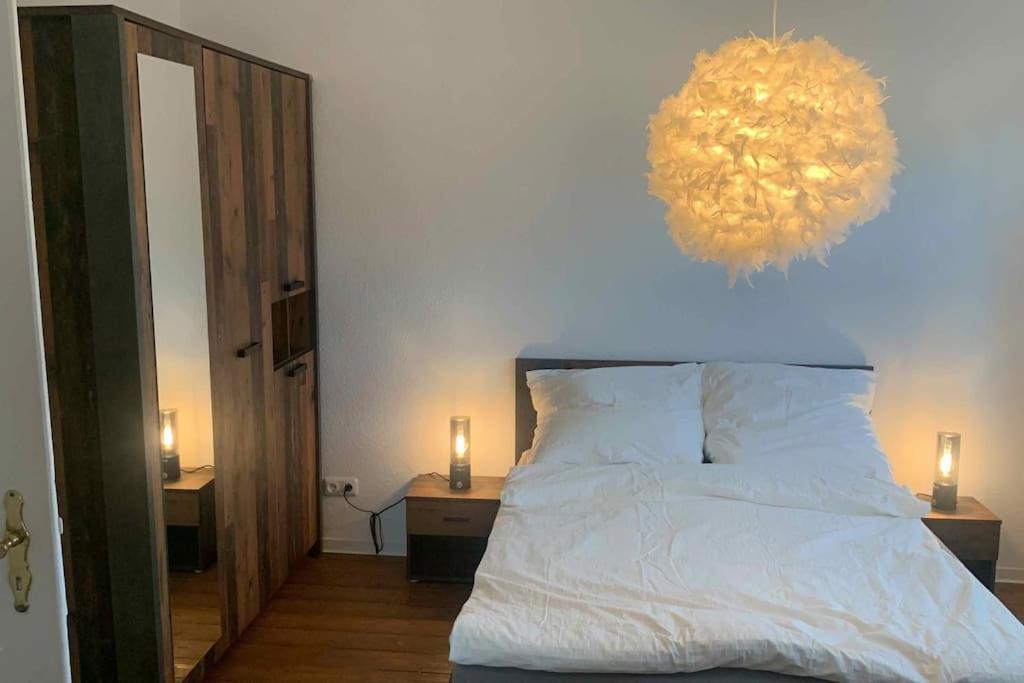 um quarto com uma cama branca e um lustre em Großzügige Wohnung Bochum-Gerthe em Bochum