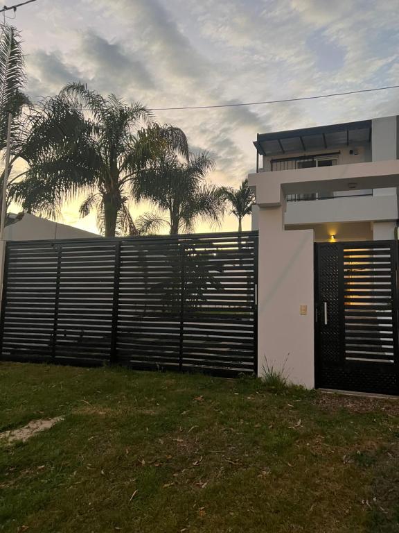 a white house with a gate and a fence at Duplex del Río in Concordia