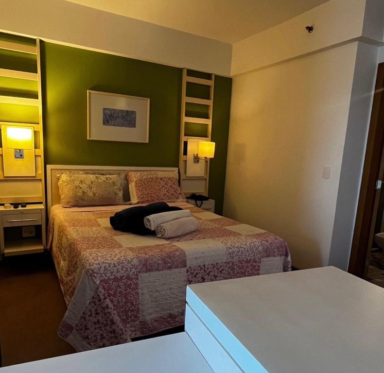 1 dormitorio con 2 camas y pared verde en FLAT EM ALPHAVILLE HOTEL CONFORT MELHOR LOCALIZAÇÃo, en Barueri