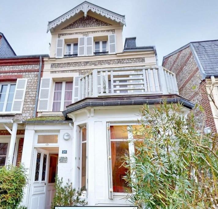 une maison blanche avec un balcon au-dessus dans l'établissement Villa Jean- plein centre Etretat, à Étretat