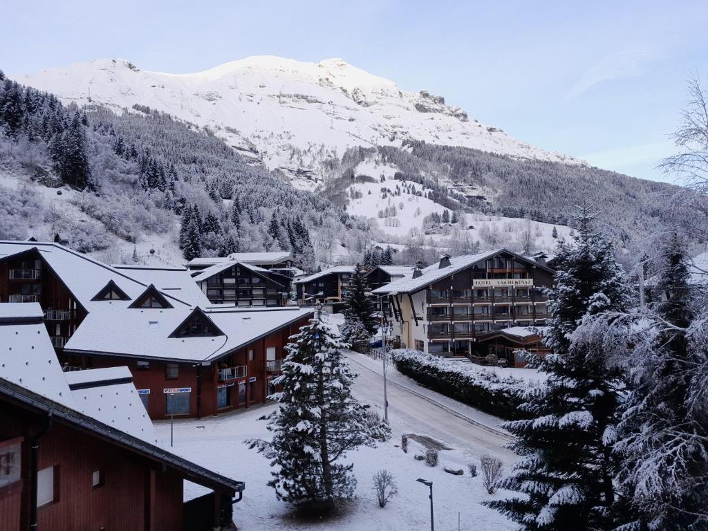 una ciudad con edificios cubiertos de nieve y una montaña en L'enclaves, en Les Contamines-Montjoie