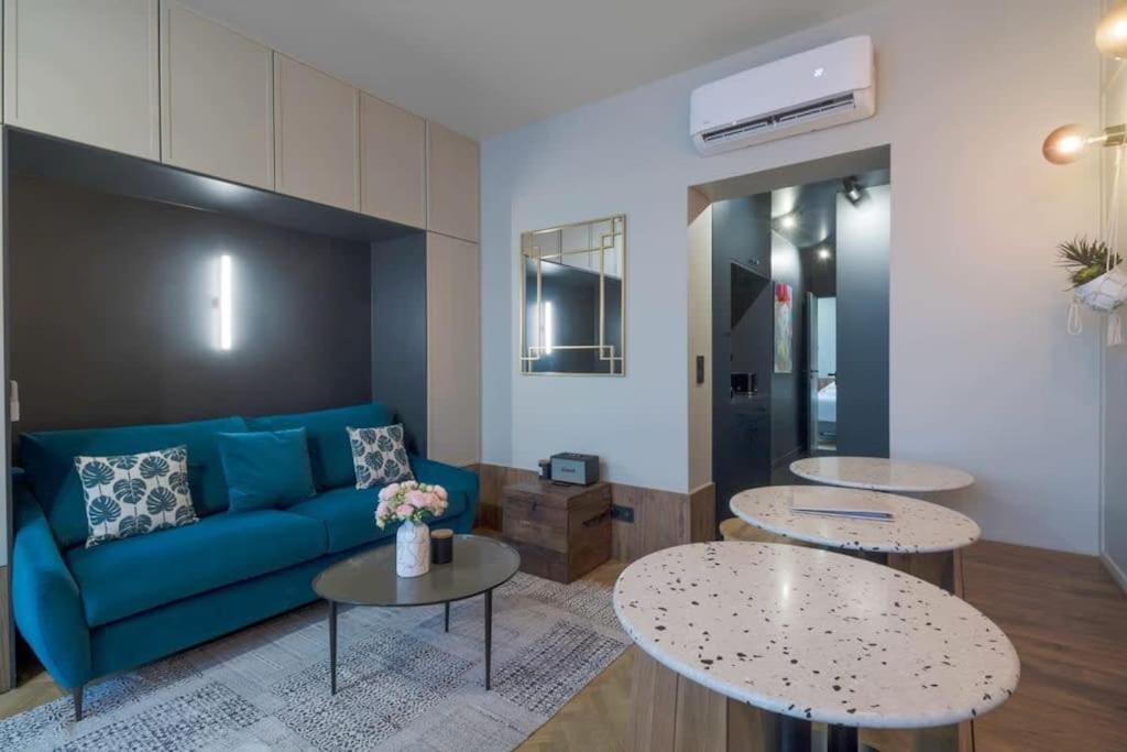 ein Wohnzimmer mit einem blauen Sofa und 2 Tischen in der Unterkunft Bel appartement pour 4 personnes in Paris