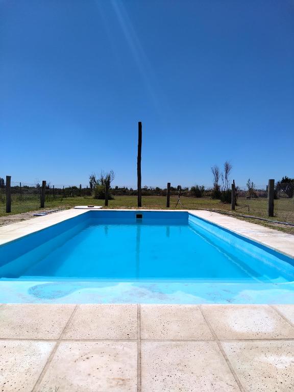 a blue swimming pool with a blue sky in the background at Entre fincas alojamiento rural in San Rafael